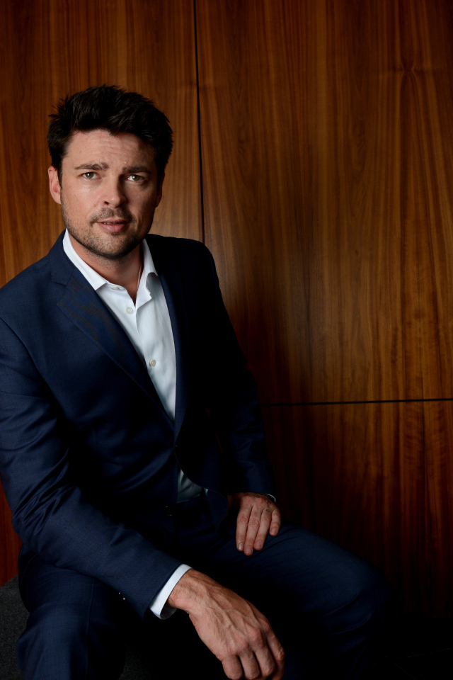 Актер Карл Урбан в костюме на фоне стены