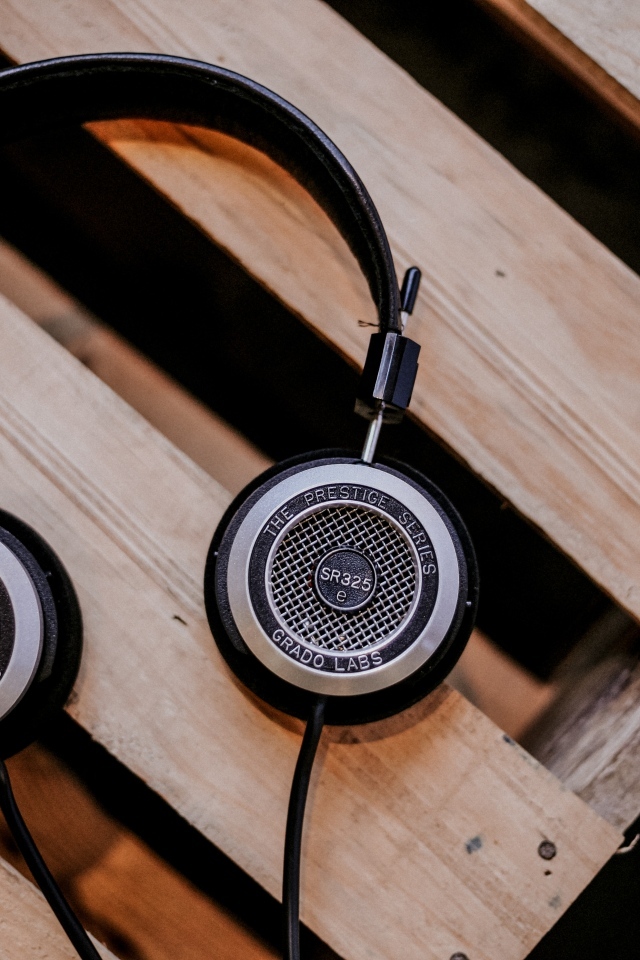 Старые наушники лежат на деревянной лавке