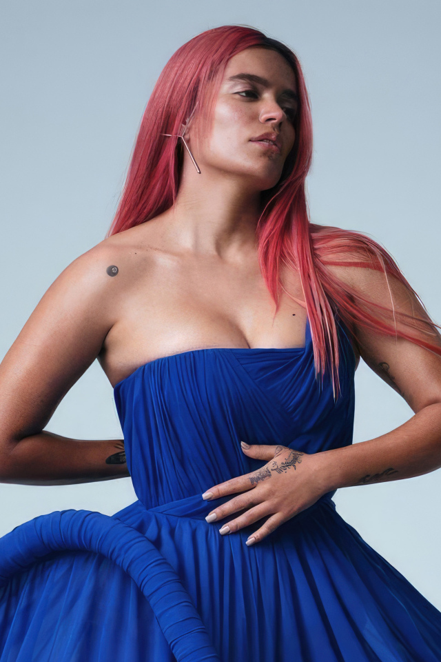 Певица Karol G в синем платье на сером фоне