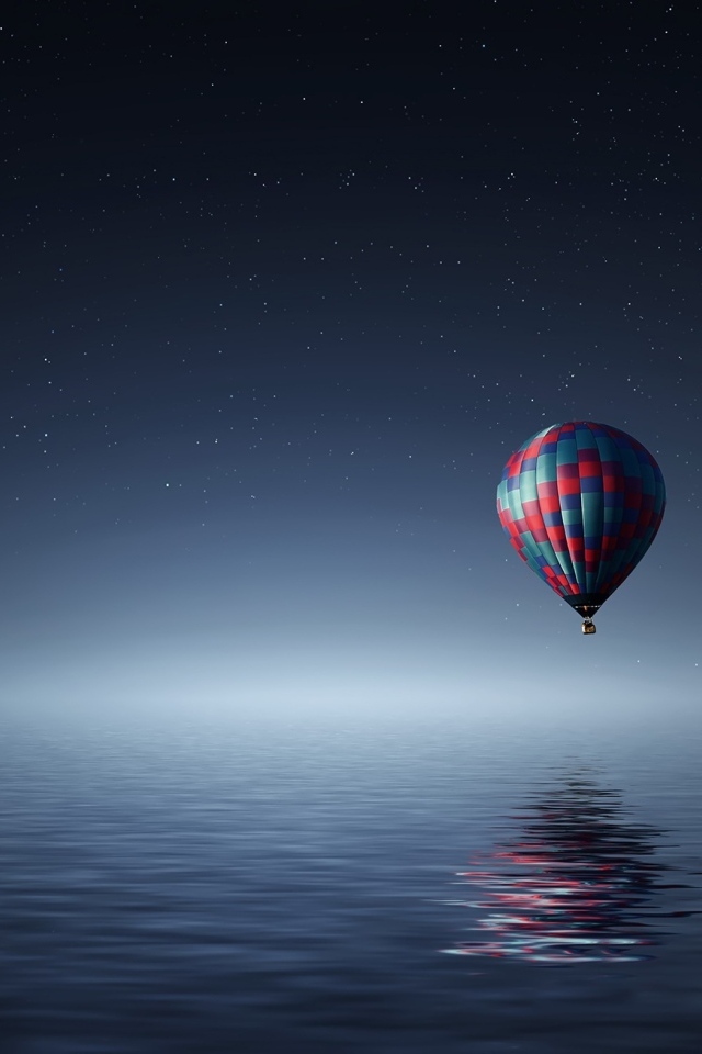 Большой воздушный шар летит над водой ночью