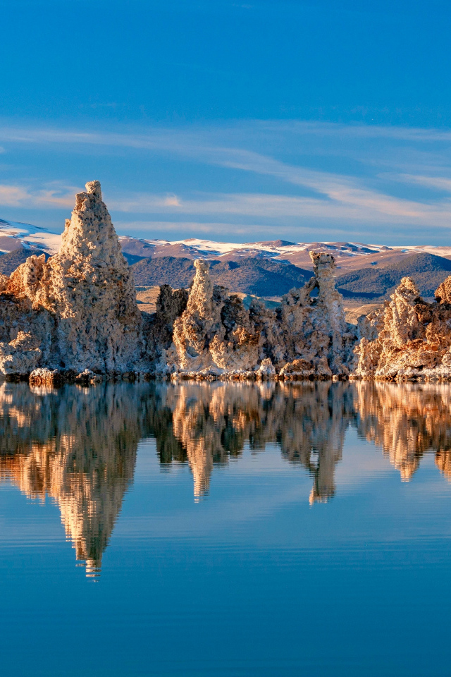 Острые скалы отражаются в тихой воде озера