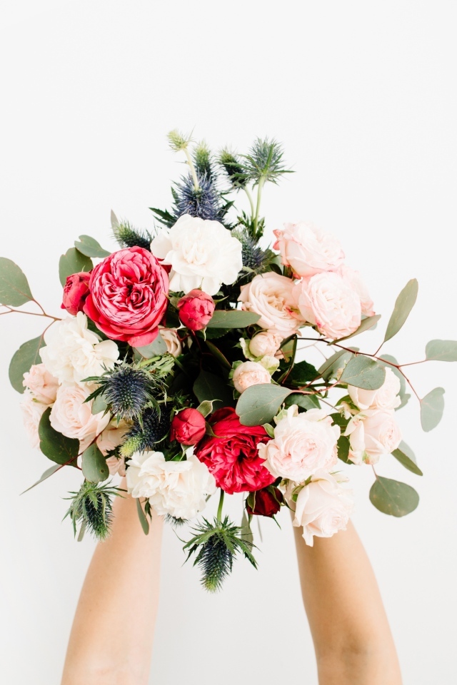 Букет цветов в руках у девушки на сером фоне