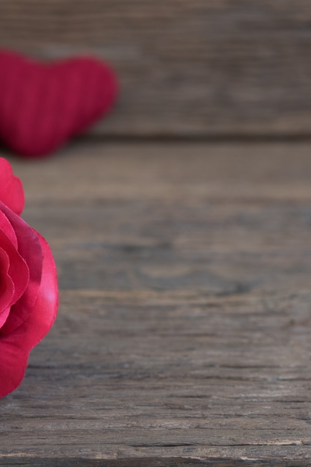 Искусственная роза на деревянном фоне с сердечками