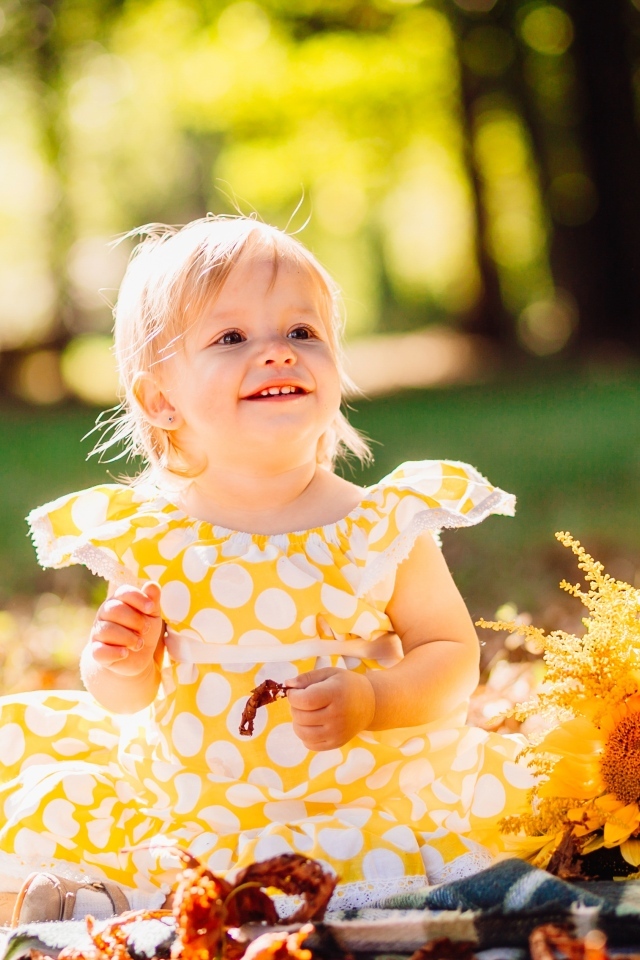 Малышка с цветами подсолнуха на траве