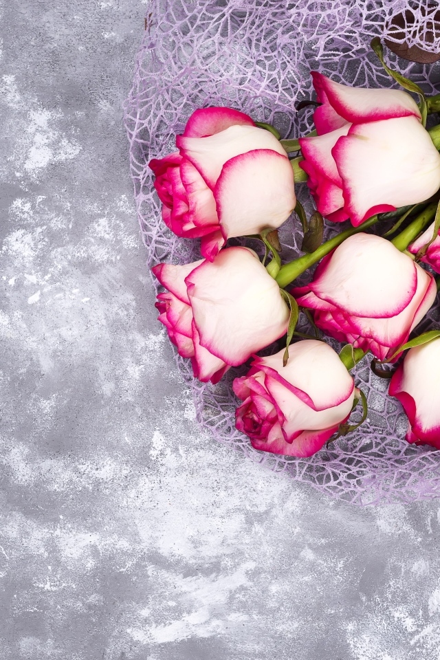 Красивый букет роз в упаковке на сером столе