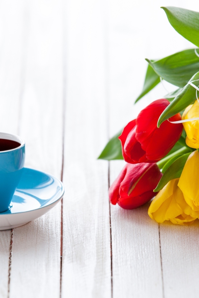 Голубая чашка на столе с букетом тюльпанов