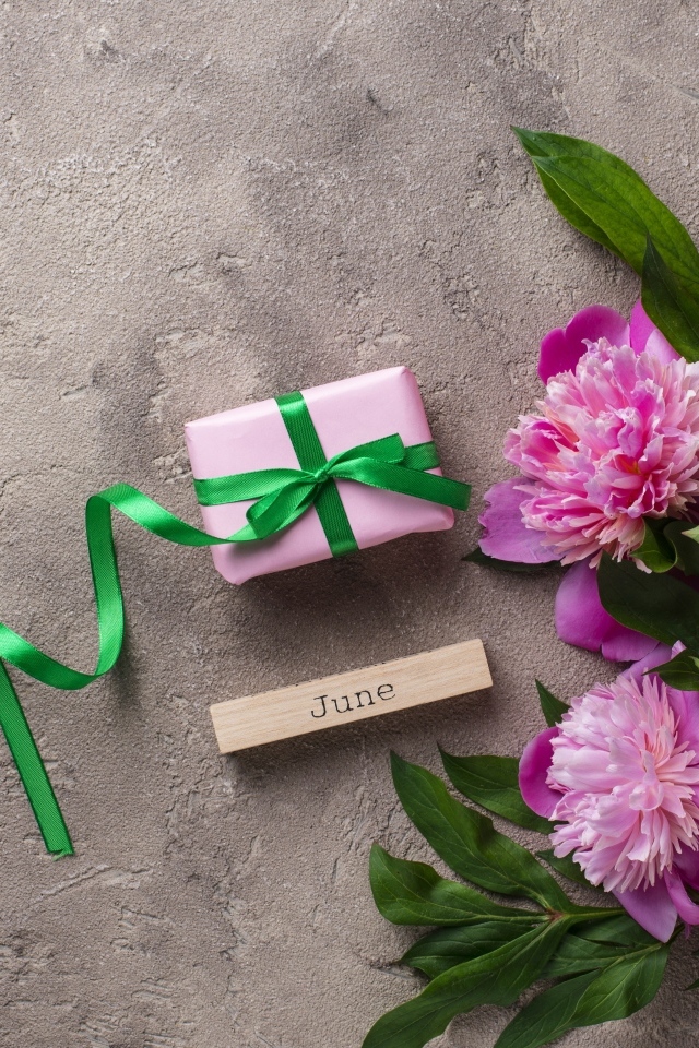 Букет розовых пионов с подарком на сером столе