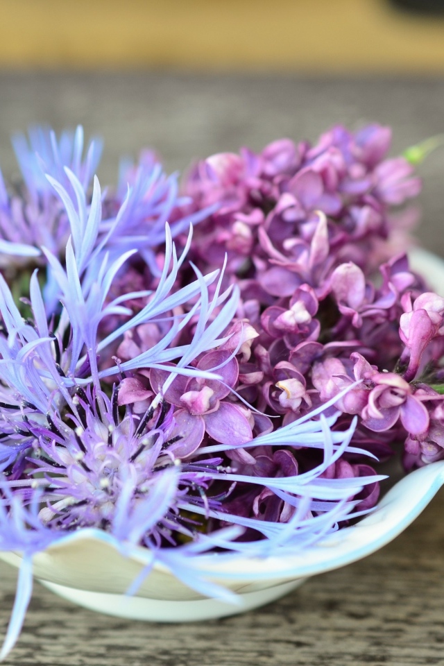 Цветы сирени и василька в вазе на столе