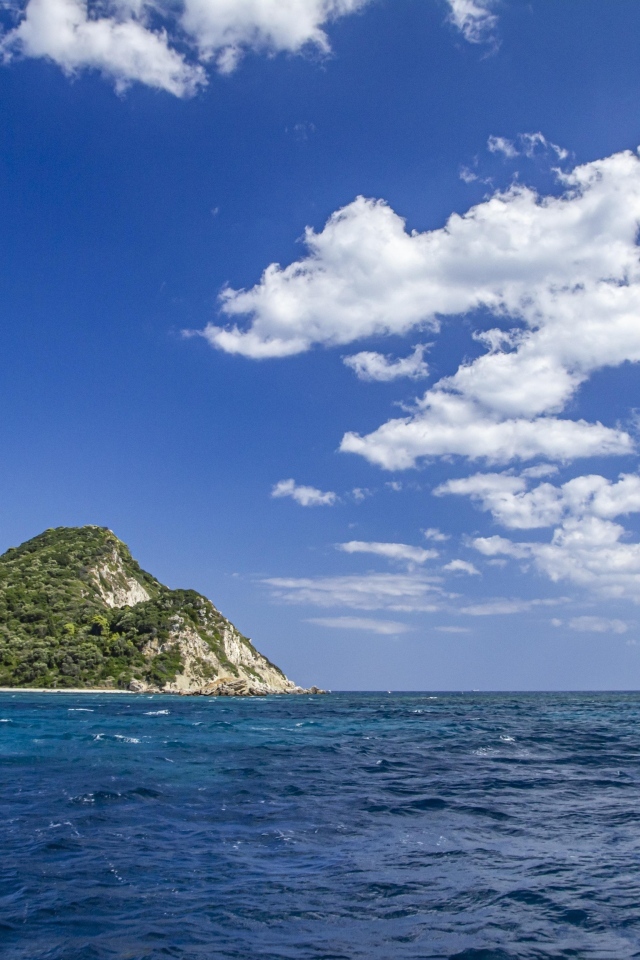 Покрытые зеленью горы в море под голубым небом