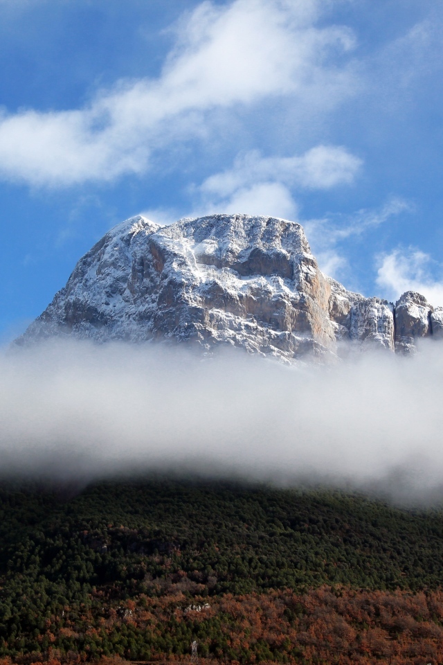 Заснеженная горная вершина в белых облаках