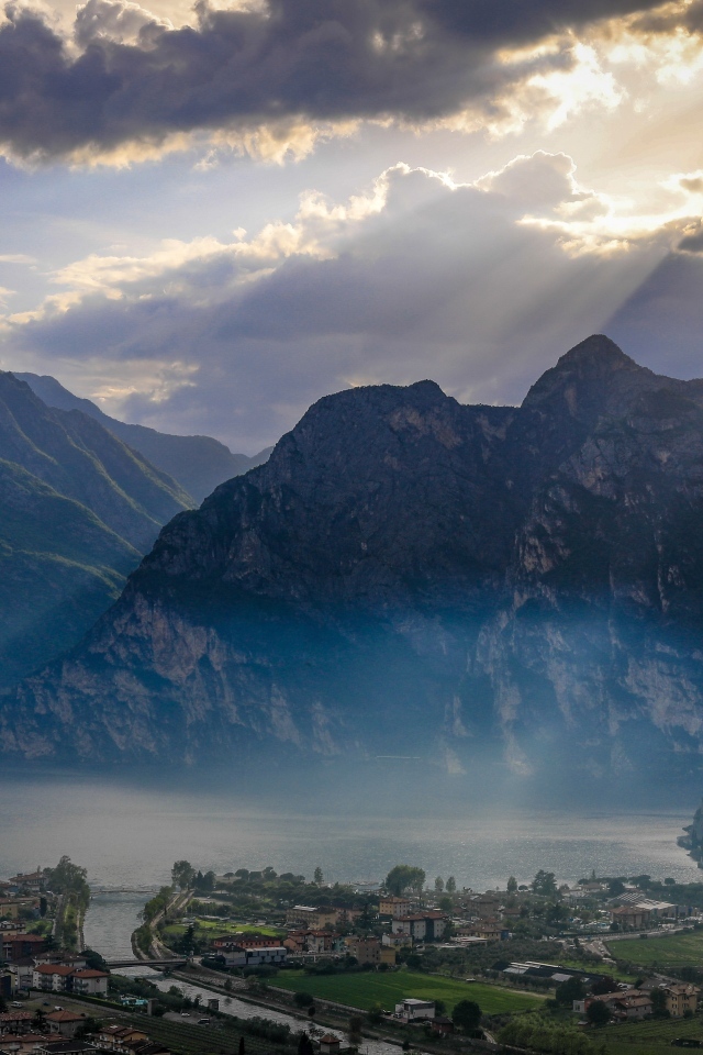 Лучи солнца покрывают горы и город 