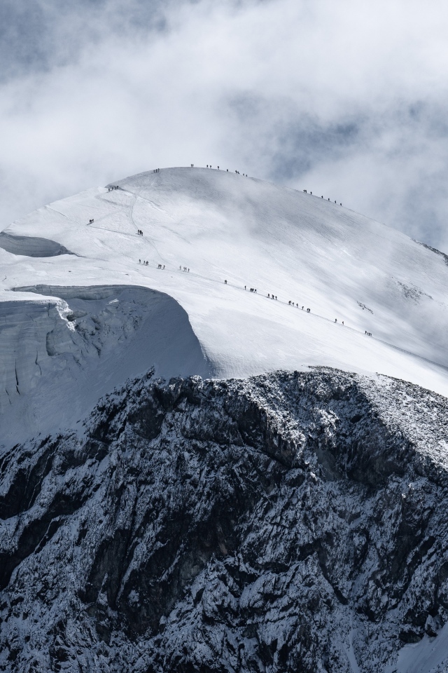 Вид на заснеженную вершину горы под белыми облаками