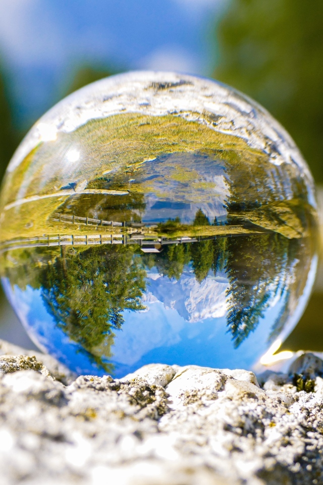 Стеклянный шар стоит на камне у воды
