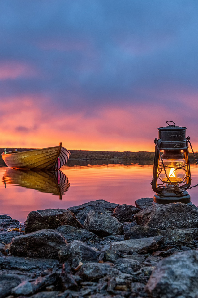 Керосиновая лампа стоит на камнях у озера