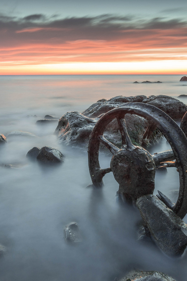 Старые колеса лежат в воде с камнями