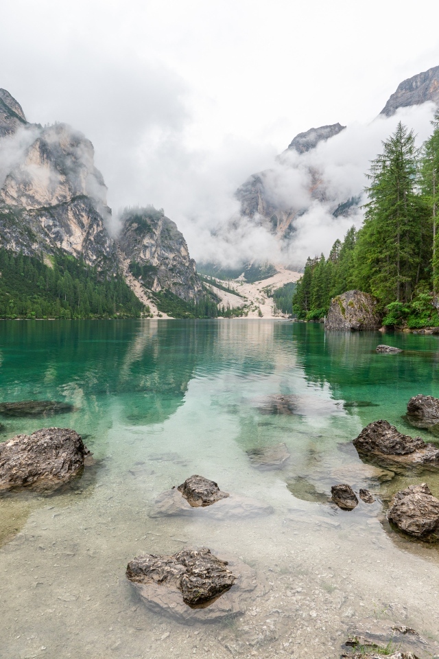 Камни лежат в воде озера в холодных горах