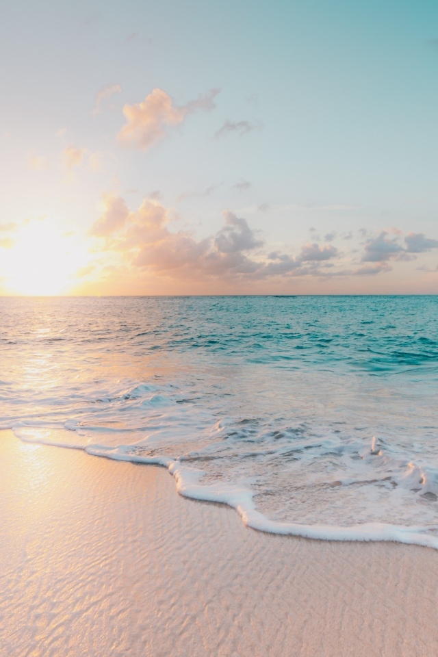 Красивая вода океана на песке в лучах закатного солнца