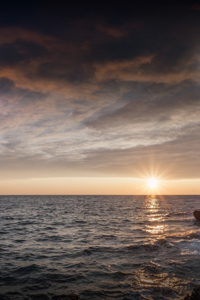 Высокий маяк на берегу моря на закате