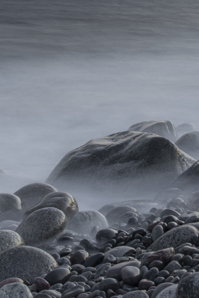 Большие черные камни на берегу моря в тумане