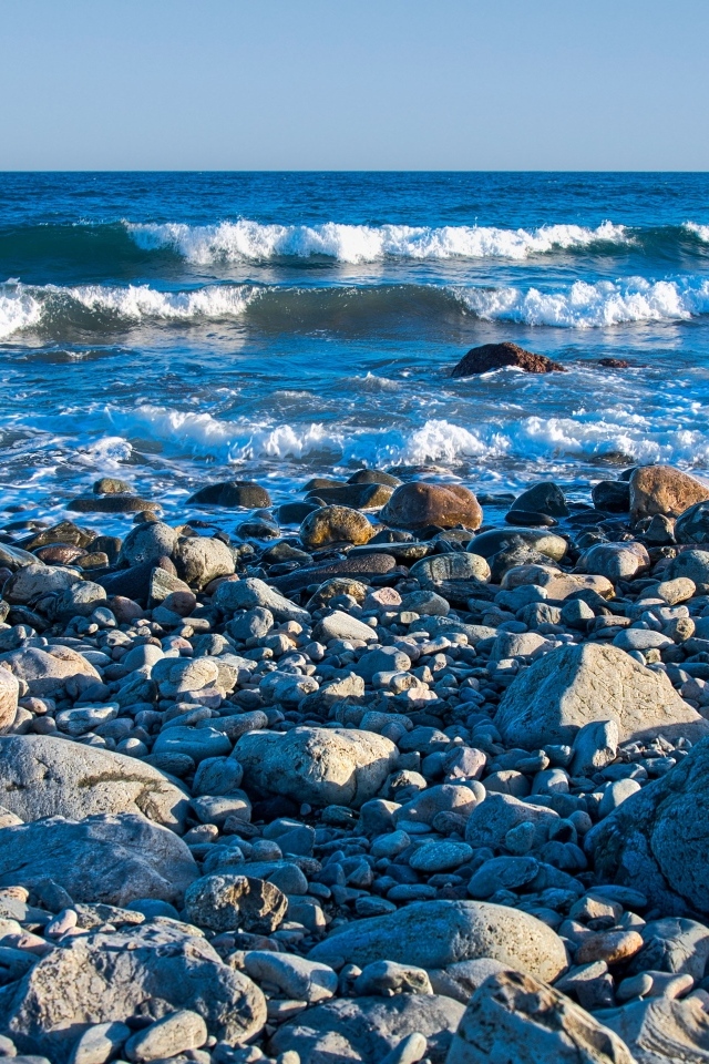 Large stones on the seashore with white waves