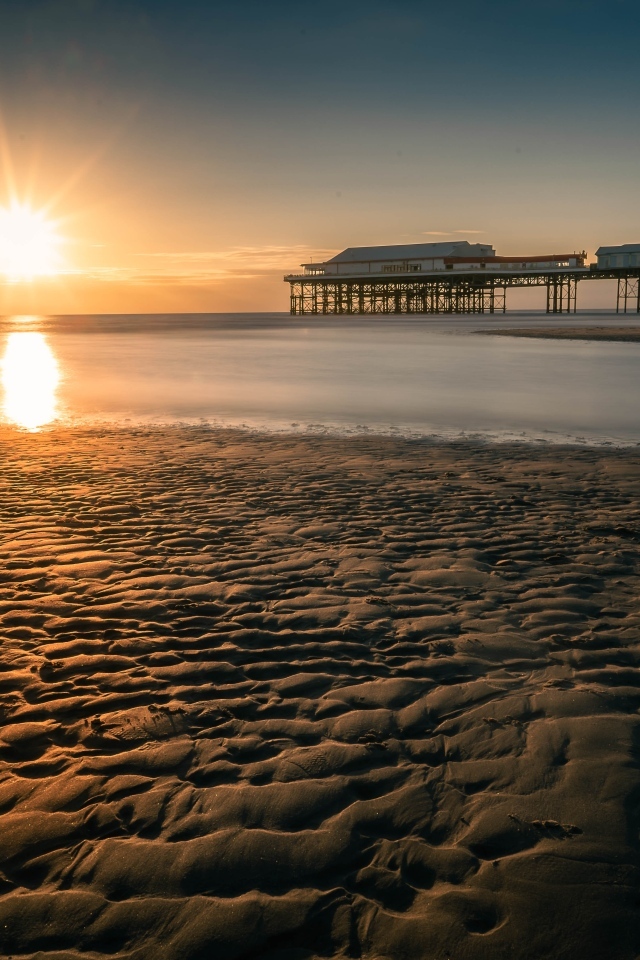 Мокрый песок на берегу моря на закате