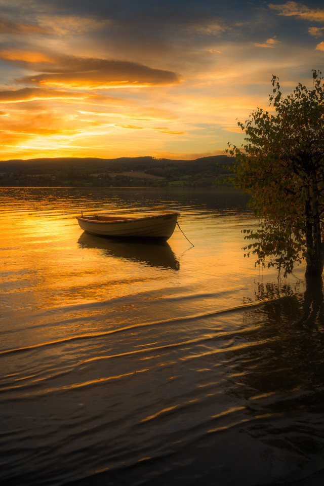 Лодка в воде спокойного озера на закате солнца