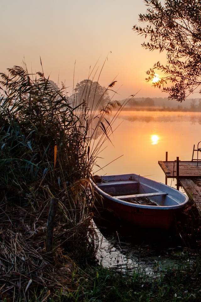 Лодка на берегу озера на закате 
