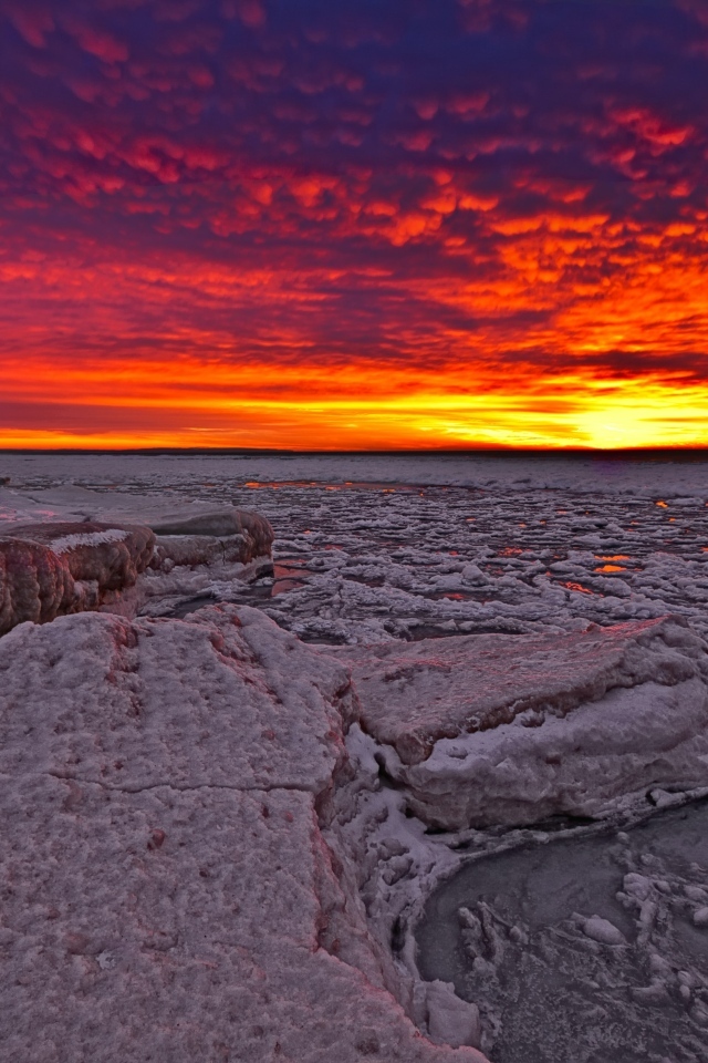 Красный закат солнца покрывает заледеневшее озеро 