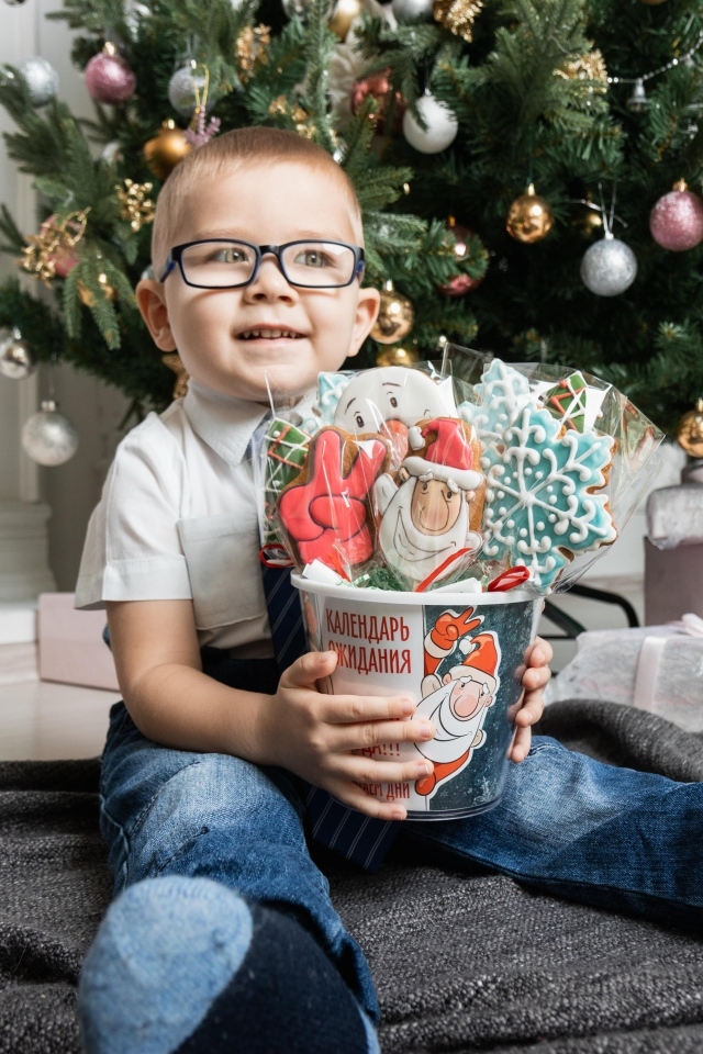 Маленький мальчик с печеньем сидит у ели