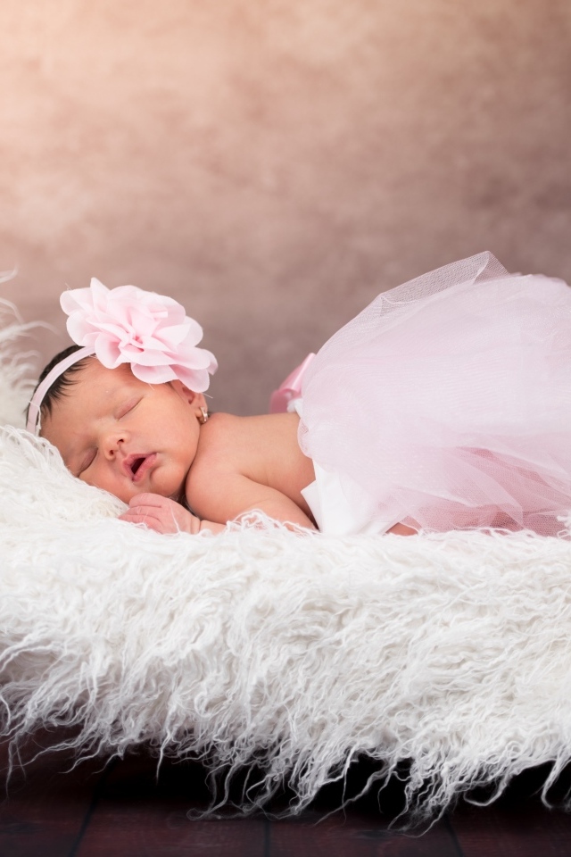 Грудной спящий ребенок в розовой юбке на кровати 