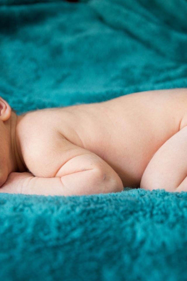 Грудной ребенок спит на синем пледе