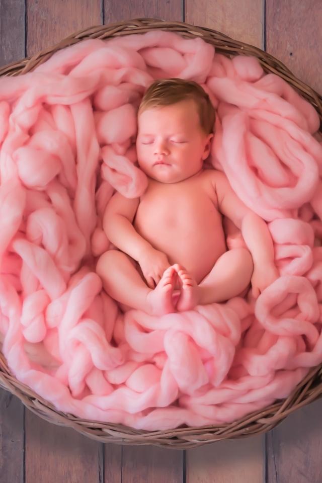 Ребенок спит в корзине с розовым покрывалом