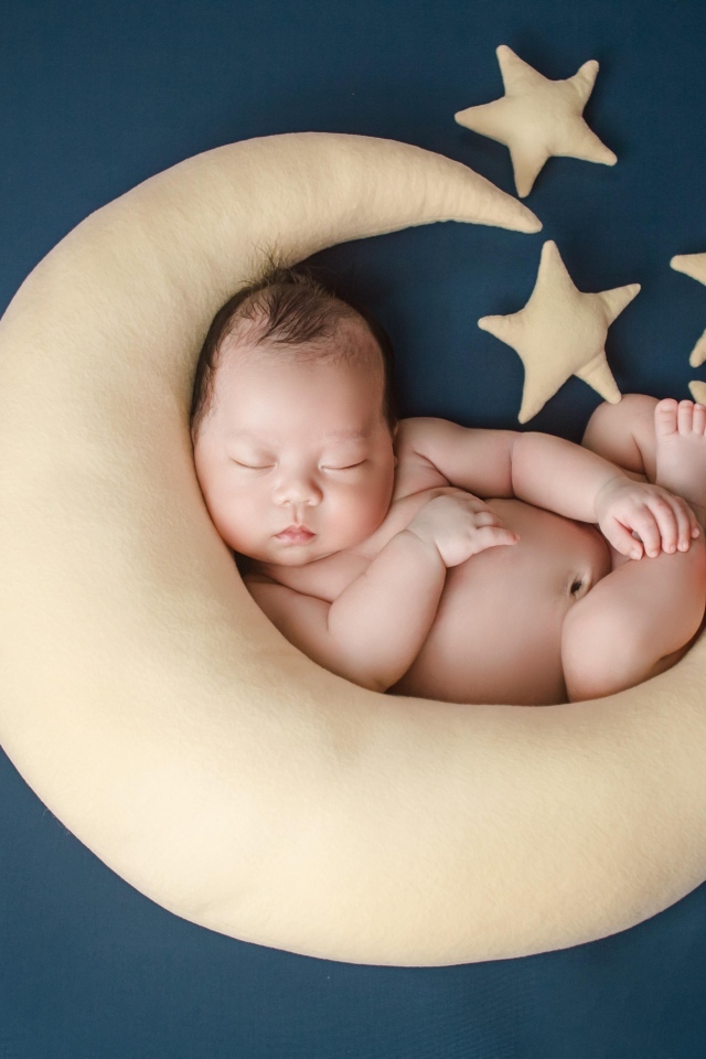 Ребенок спит на игрушечном месяце