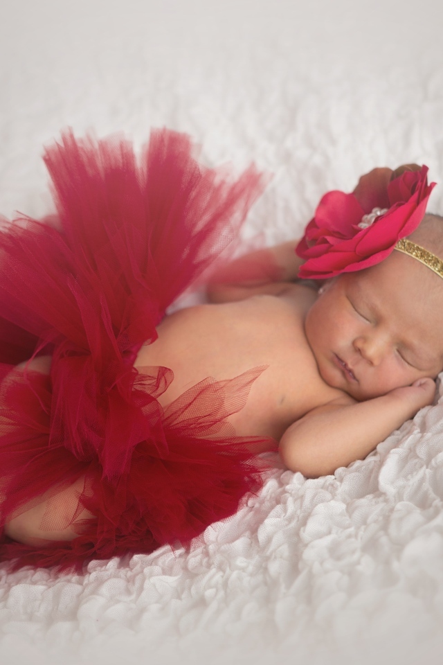 Красивая пышная красная юбка и бант на спящей малышке