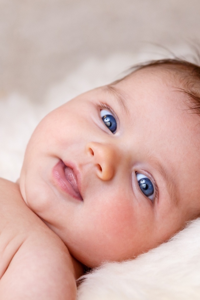 Голубоглазая новорожденная малышка с цветком на голове