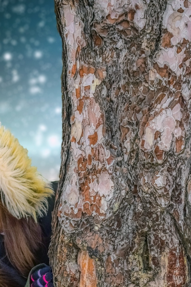 Мальчик и девочка стоят у дерева зимой