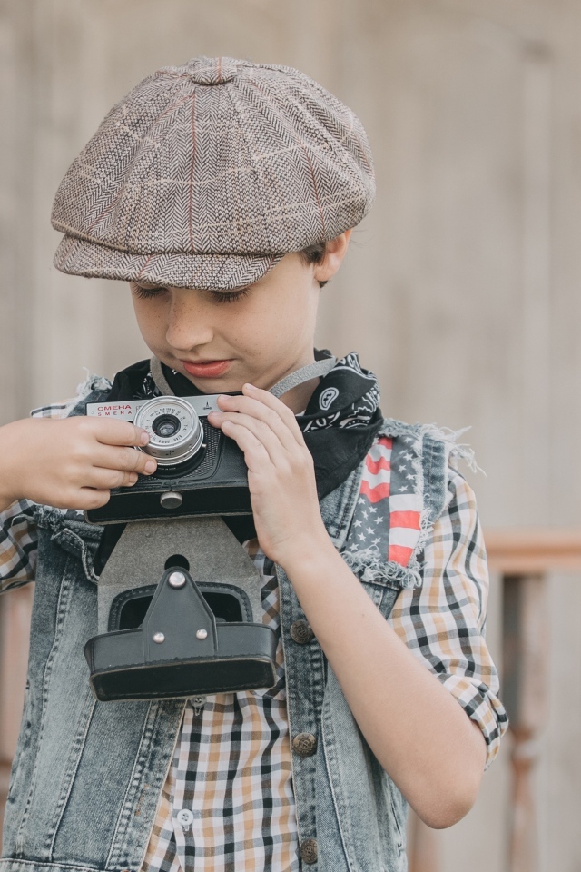 Мальчик в кепке с фотоаппаратом в руках