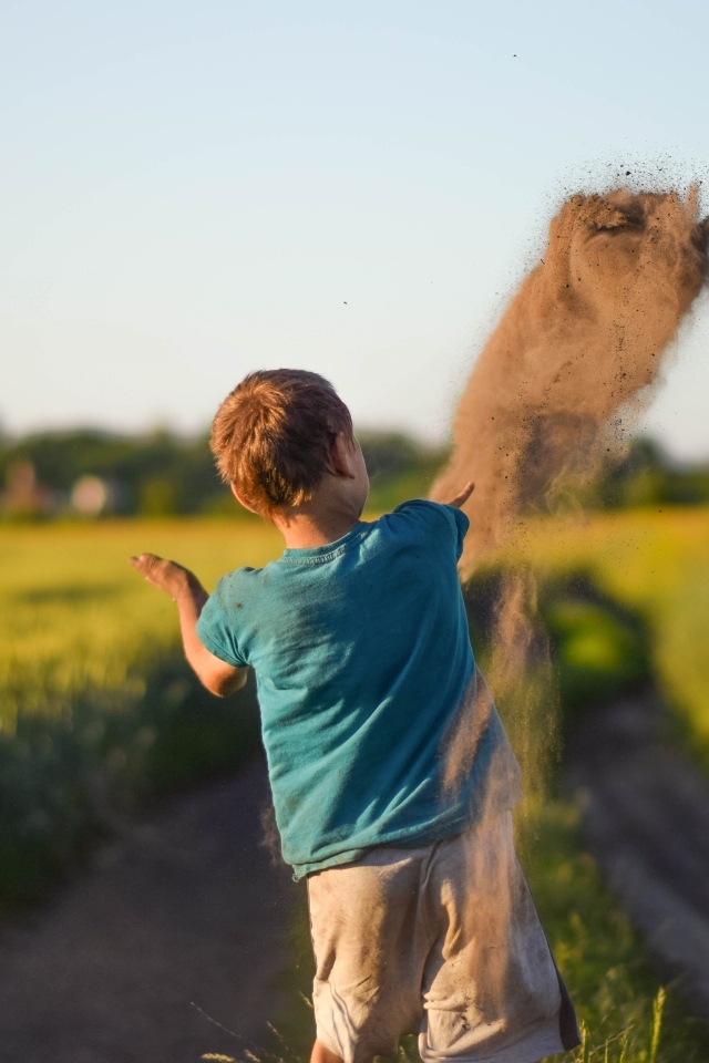 Мальчик бросает песок на дороге