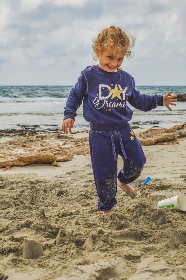 Веселая девочка играет на песке на пляже