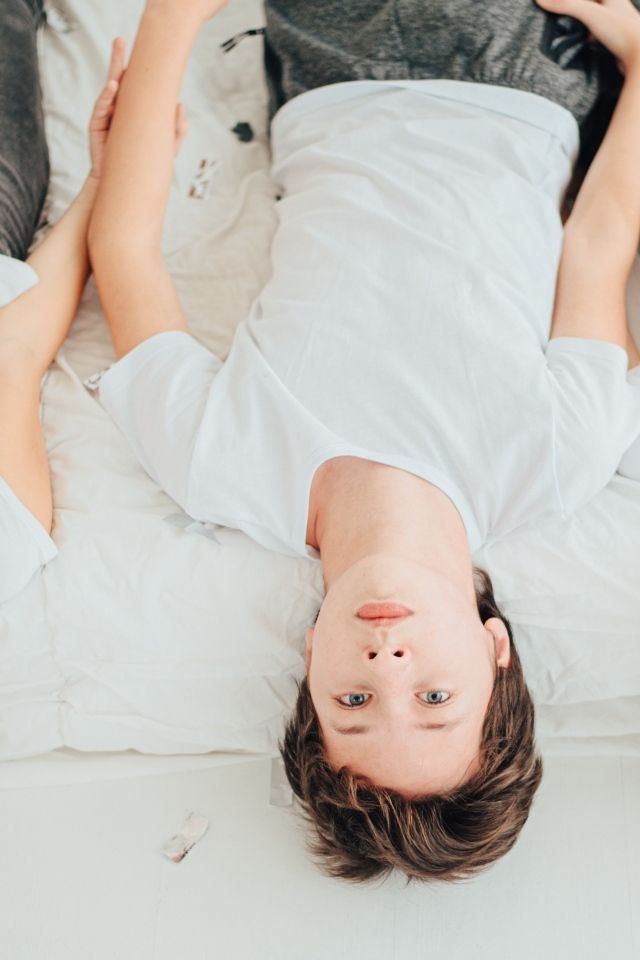 Дети в белых футболках лежат на кровати