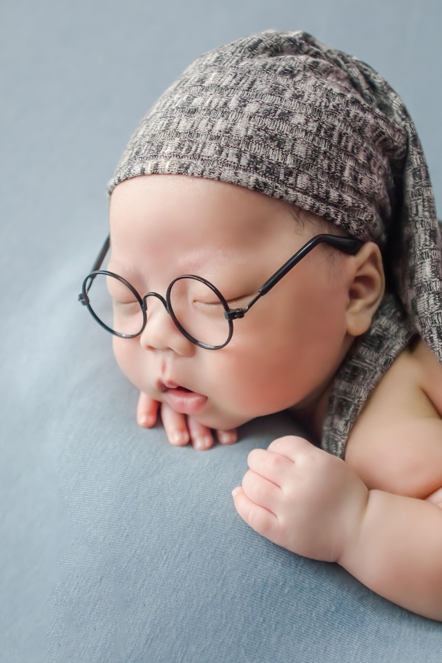 Забавный малыш в очках одет в серый костюм