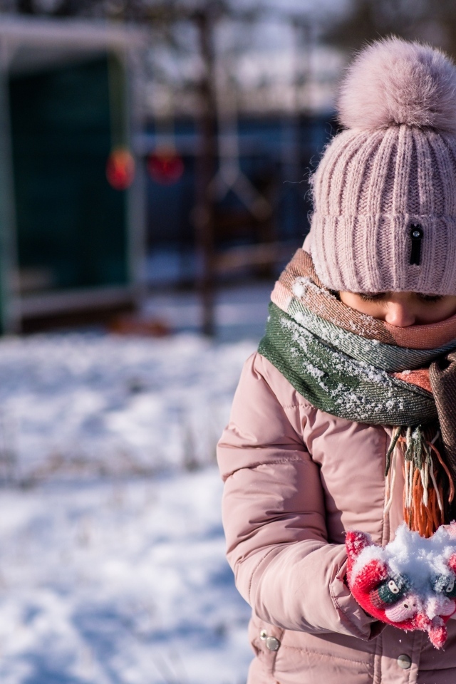 Девочка держит снег в руках зимой