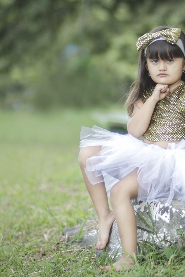 Девочка в красивом платье сидит на камне