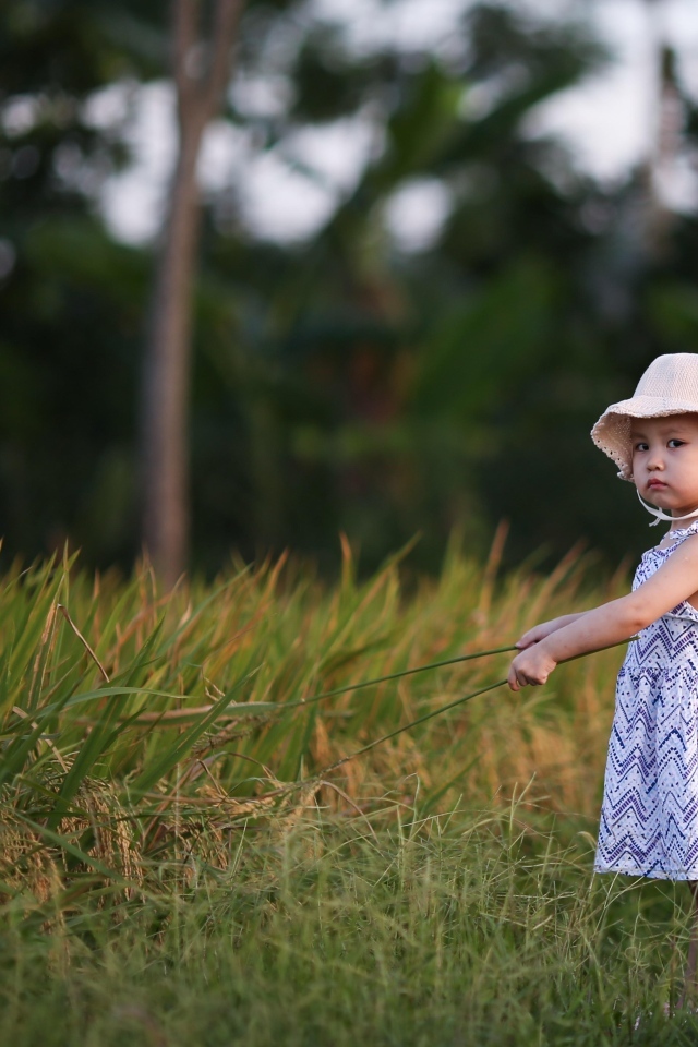Девочка в платье стоит на траве 
