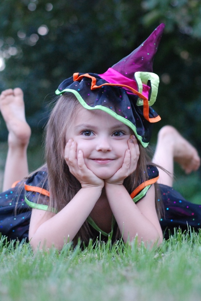 Девочка в костюме лежит на зеленой траве