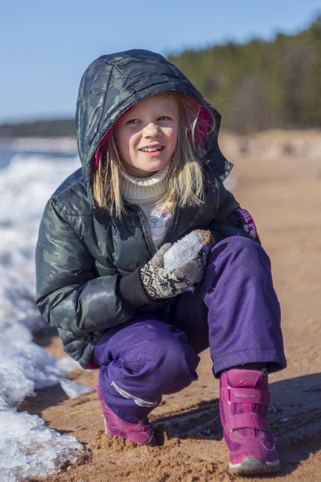 Девочка сидит у замерзшего озера 