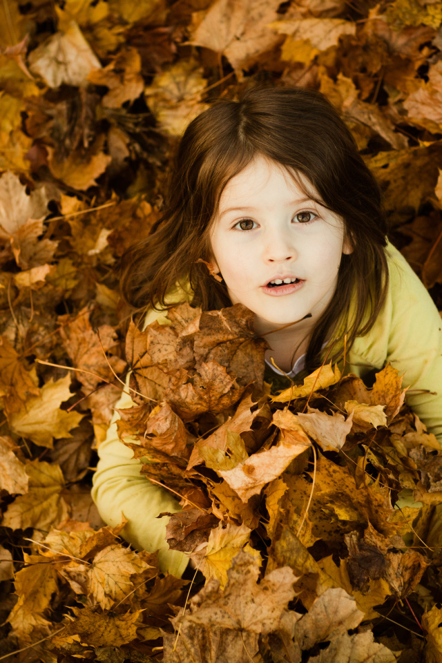 Девочка сидит в опавшей листве