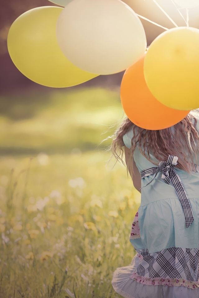 Девочка с шариками бегает по траве