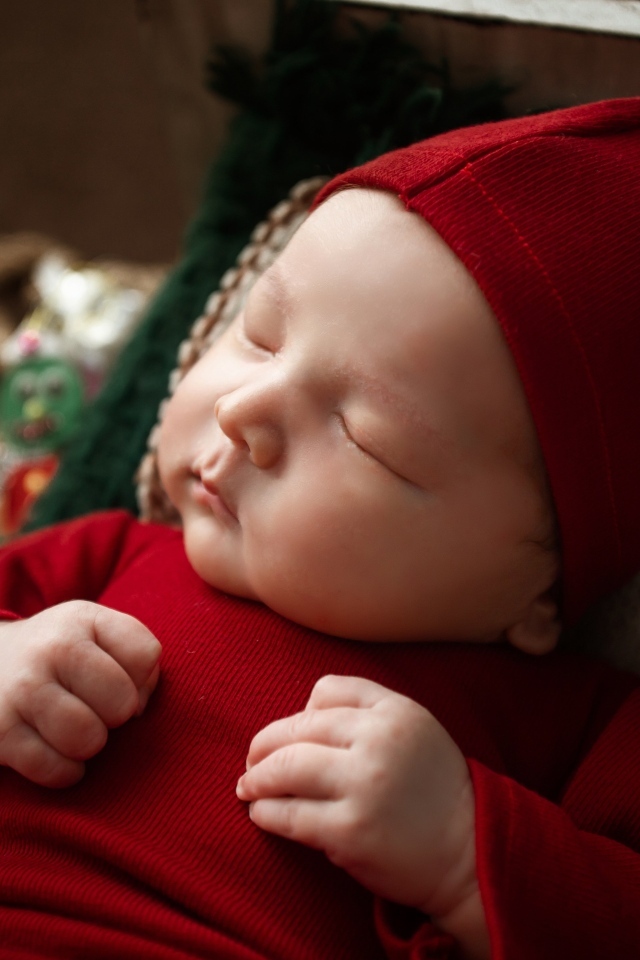 Маленький ребенок спит в красном костюме