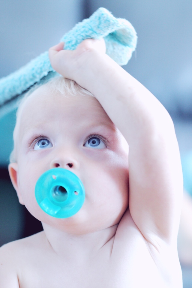 Маленький ребенок с голубой соской во рту